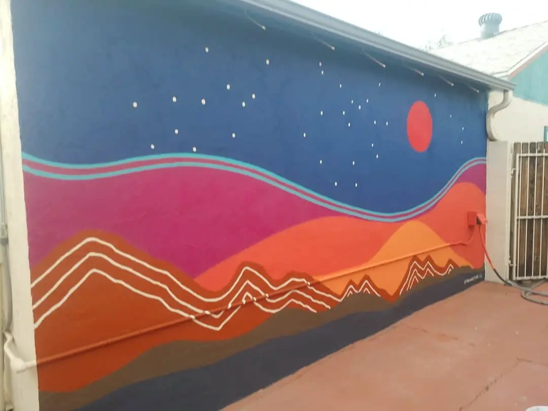 Night-sky mural with a deep blue field, red circle, and layered pink and orange mountain forms.