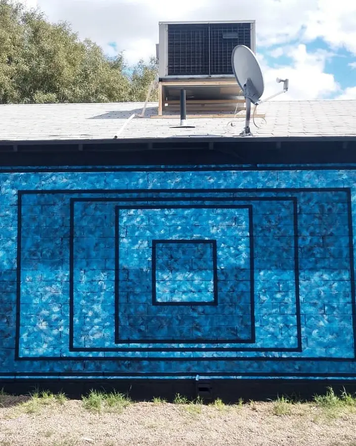 Straight-on view of a blue textured mural made from nested black rectangular outlines on an exterior wall.