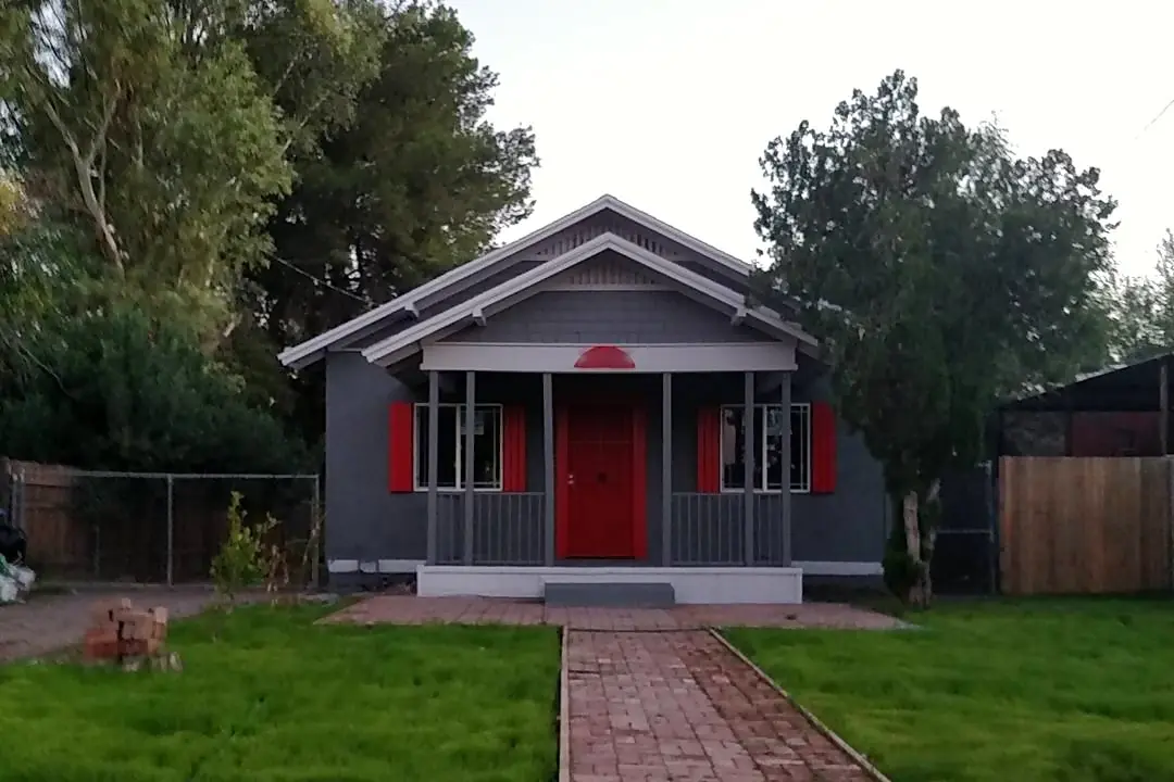 Small Craftsman home after painting, with a charcoal facade, red door and accents, and pale porch trim.
