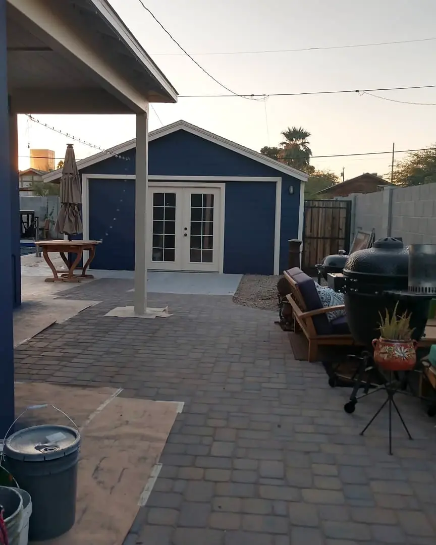 Backyard view of a freshly painted navy garage with white French doors and trim.