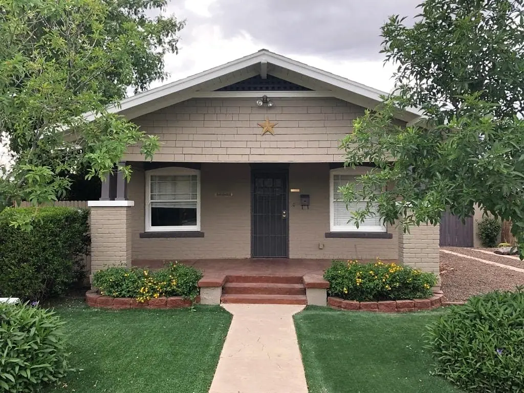 Finished heritage bungalow with taupe masonry, white trim, and dark architectural details.
