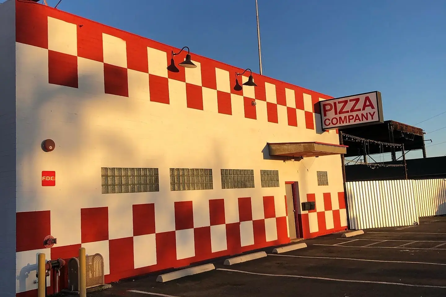 Red and white checkerboard commercial exterior photographed in warm late-day light.