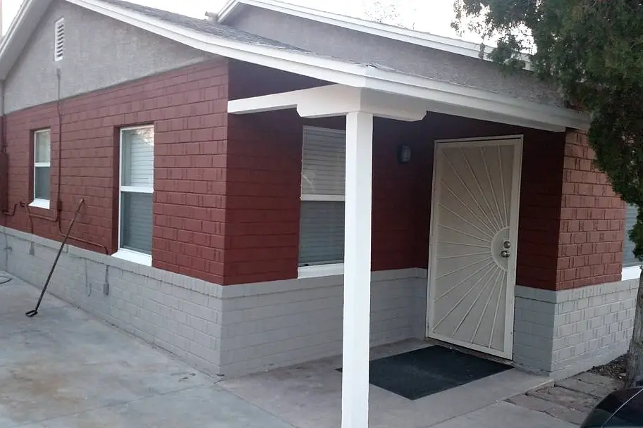 Covered porch finished with brick red walls, pale gray masonry, and crisp white posts and beams.