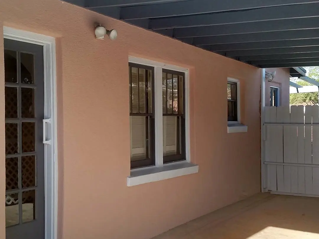 Covered patio with peach stucco walls, bright white window trim, and a dark blue-gray ceiling.