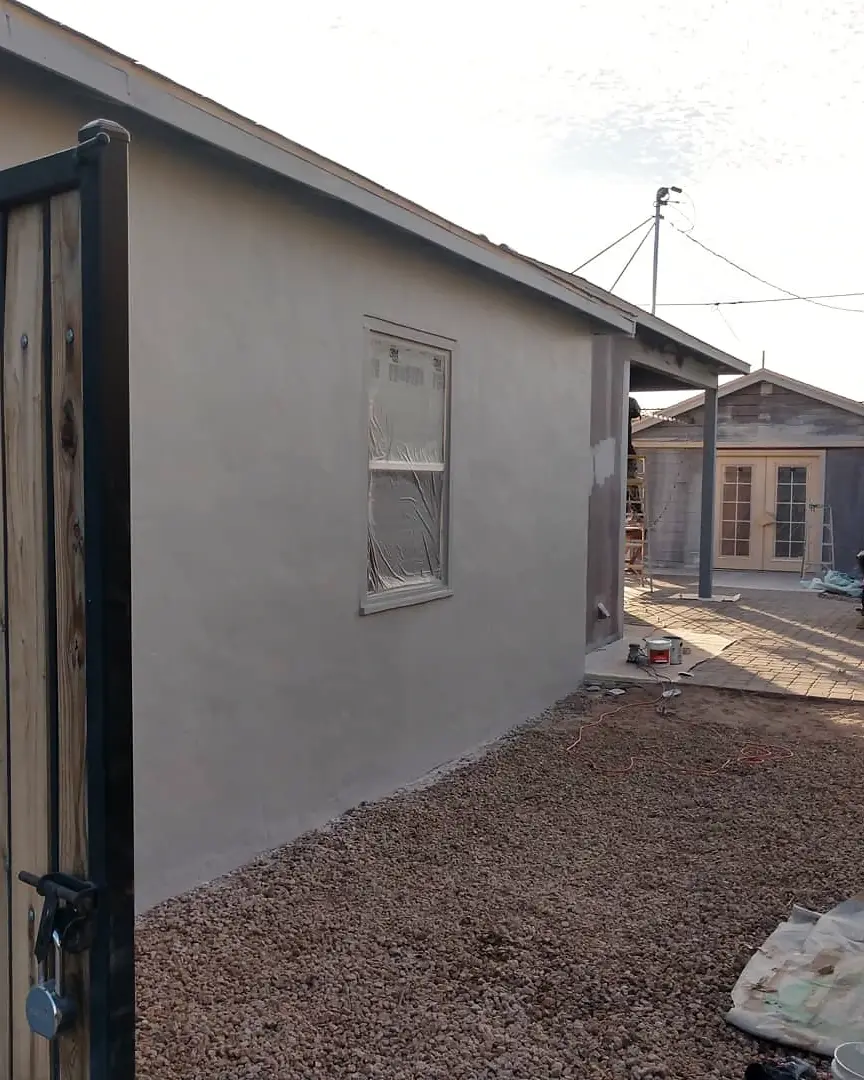 Side wall during exterior preparation, with a masked window and fresh light-colored coating.